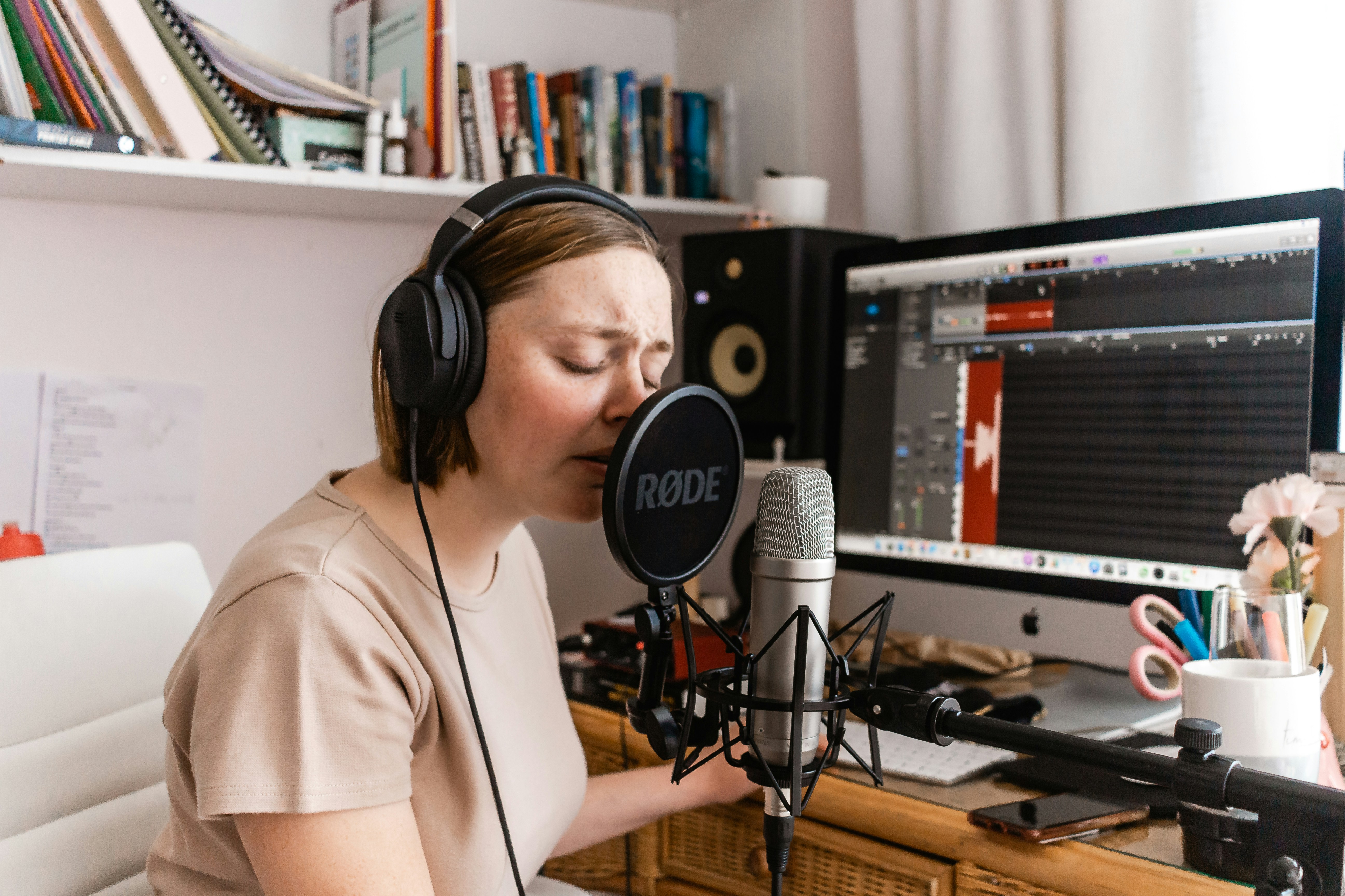 Female podcast host recording in home studio, showing DIY podcast setup